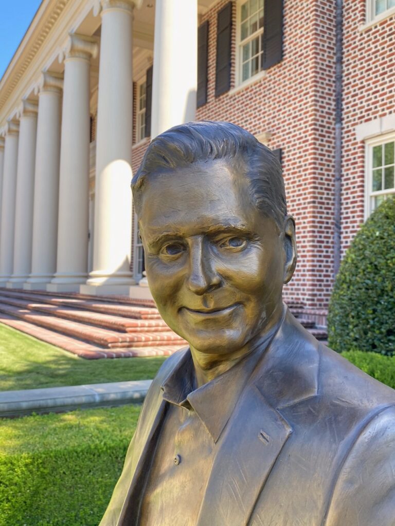 Bronze male portrait statue near columned building
