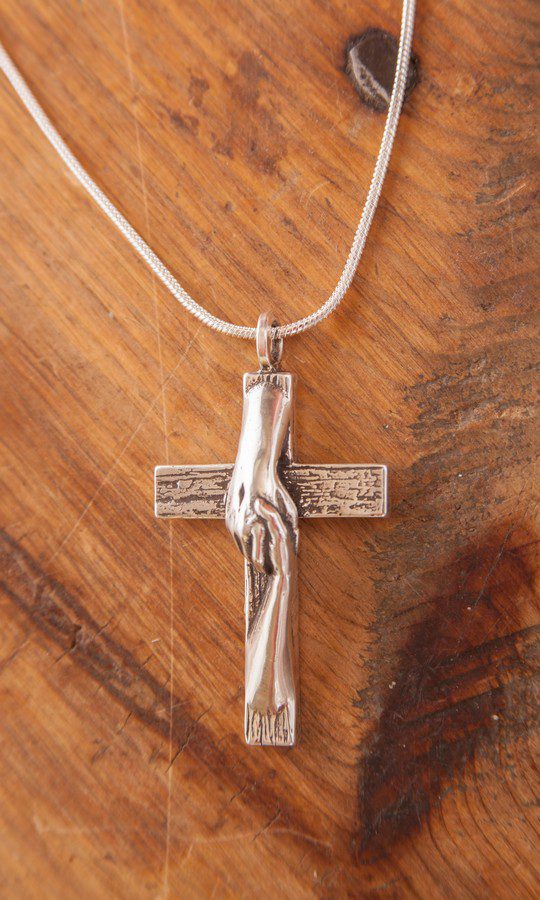 Tom White Studios, Inc | Cross Sculptures Calvary Jesus Rescued Statue Rescued Cross silver necklace created by Christian sculptor, Tom White. Depicts Jesus nail-scarred hand rescuing mankind by His great love shown on Calvary by His death and the power of His Resurrection. Available in necklaces and bronze wall hangings.