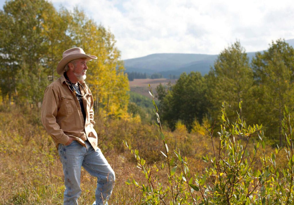Cowboy-hatted man standing in autumn meadow