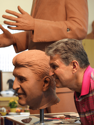 Tom White Studios, Inc | Manchin Portrait Sculpture Artist inspecting clay portrait head closely