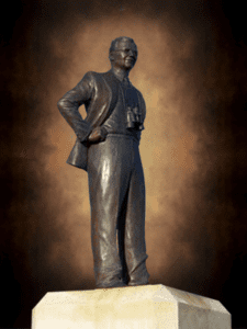 Bronze figure on stone plinth, dramatic lighting