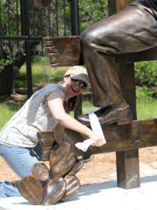 Woman kneeling beside bronze statue base