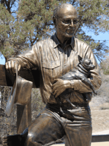 Bronze seated man sculpture holding small dog