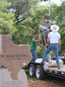 Workers guiding bronze figure off trailer