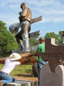 Crew hoisting bronze rancher statue during installation