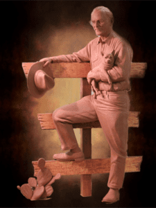 Dramatically lit sculpture of man holding small dog