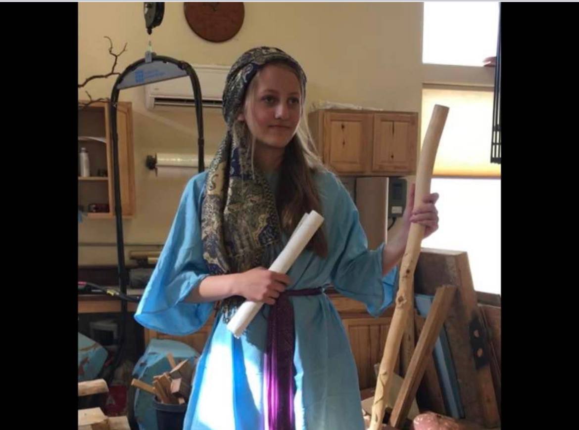 Model in blue costume holding scroll