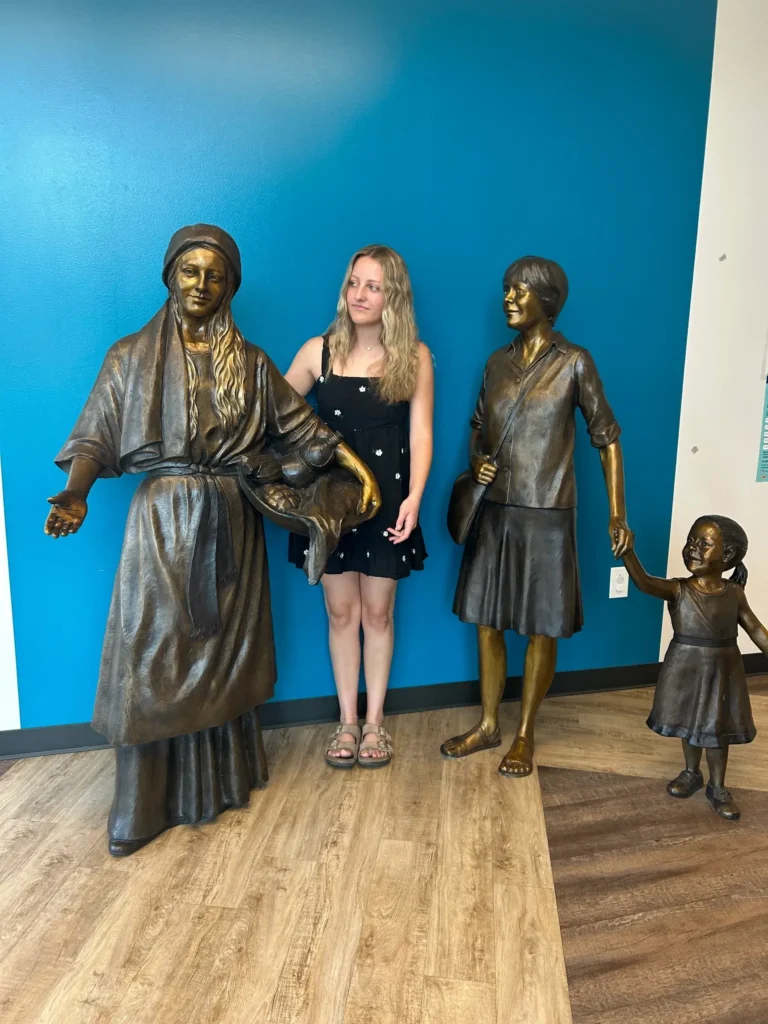 Girl posing between bronze figures